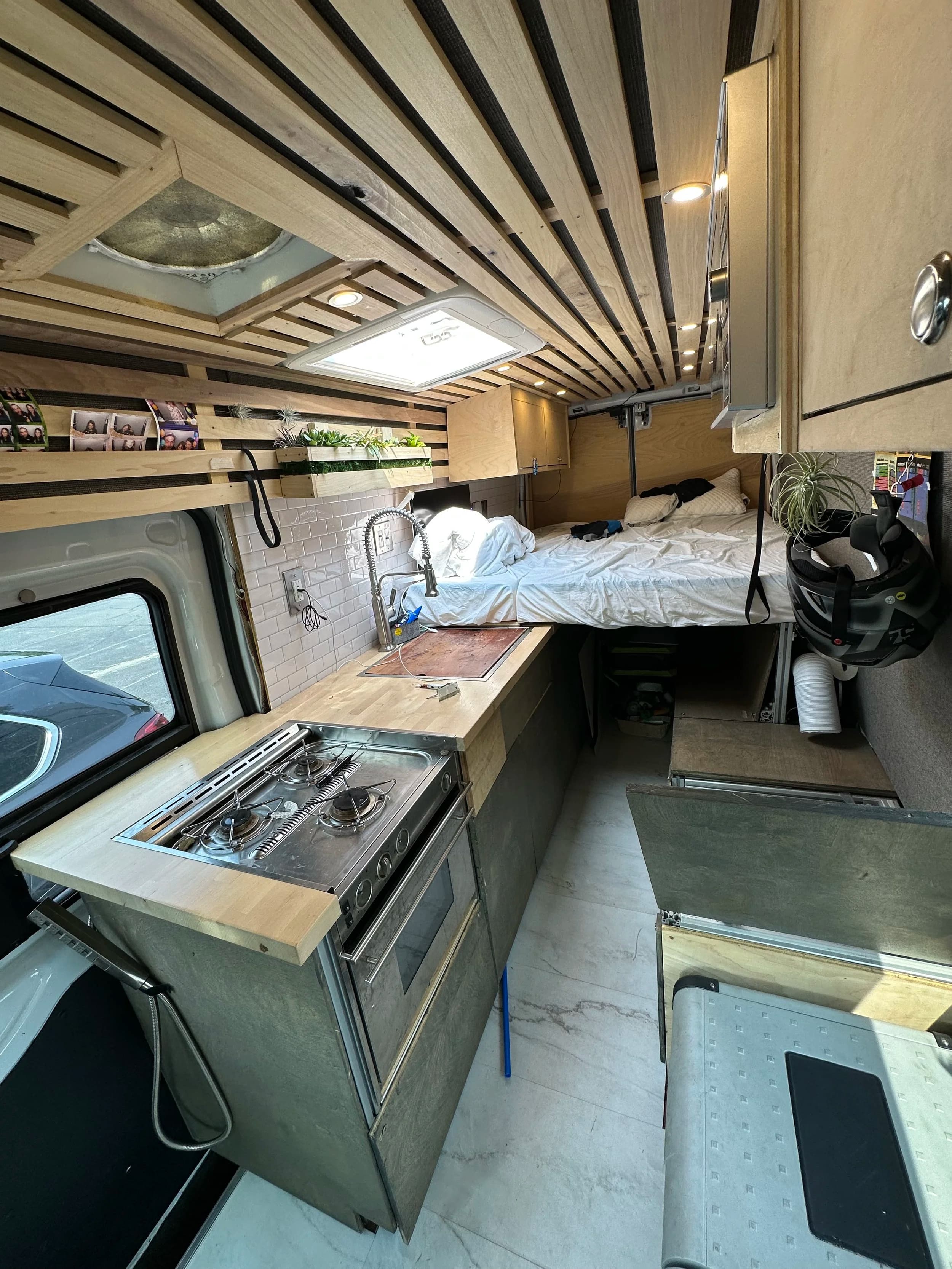 Forest Queen Van completed interior with slatted wood ceiling, kitchen, and bed